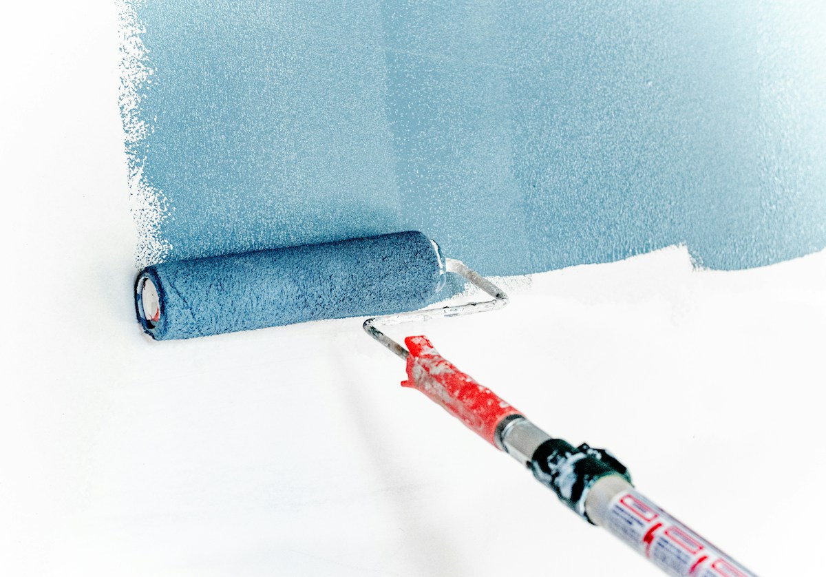 A roller applying fresh paint to a wall