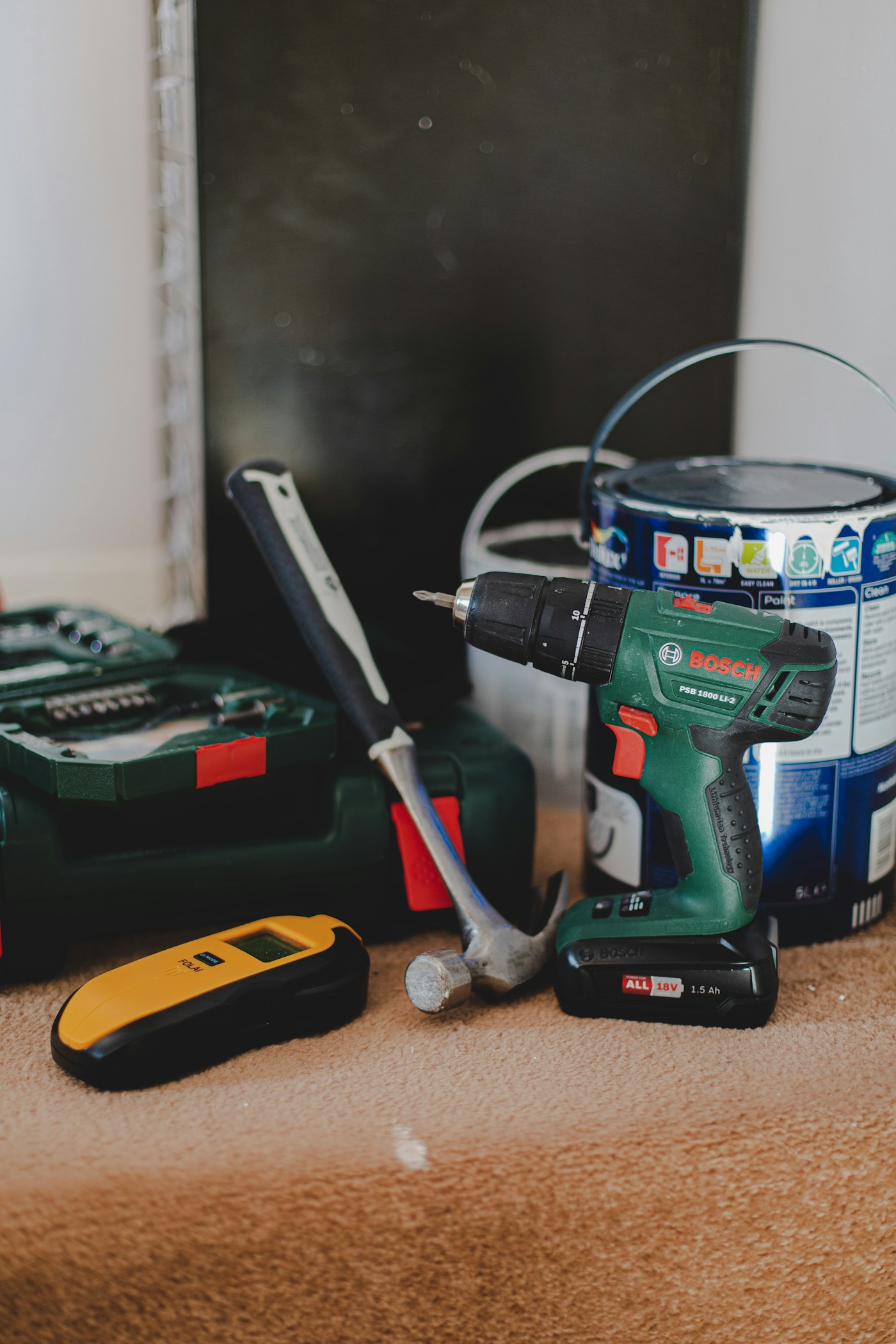 A drill, hammer, and stud finder ready for home repairs